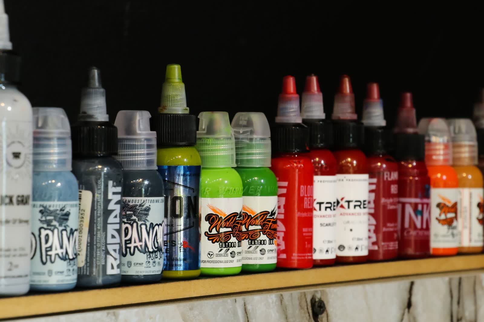Prateleira de tintas de tatuagem organizadas por marca