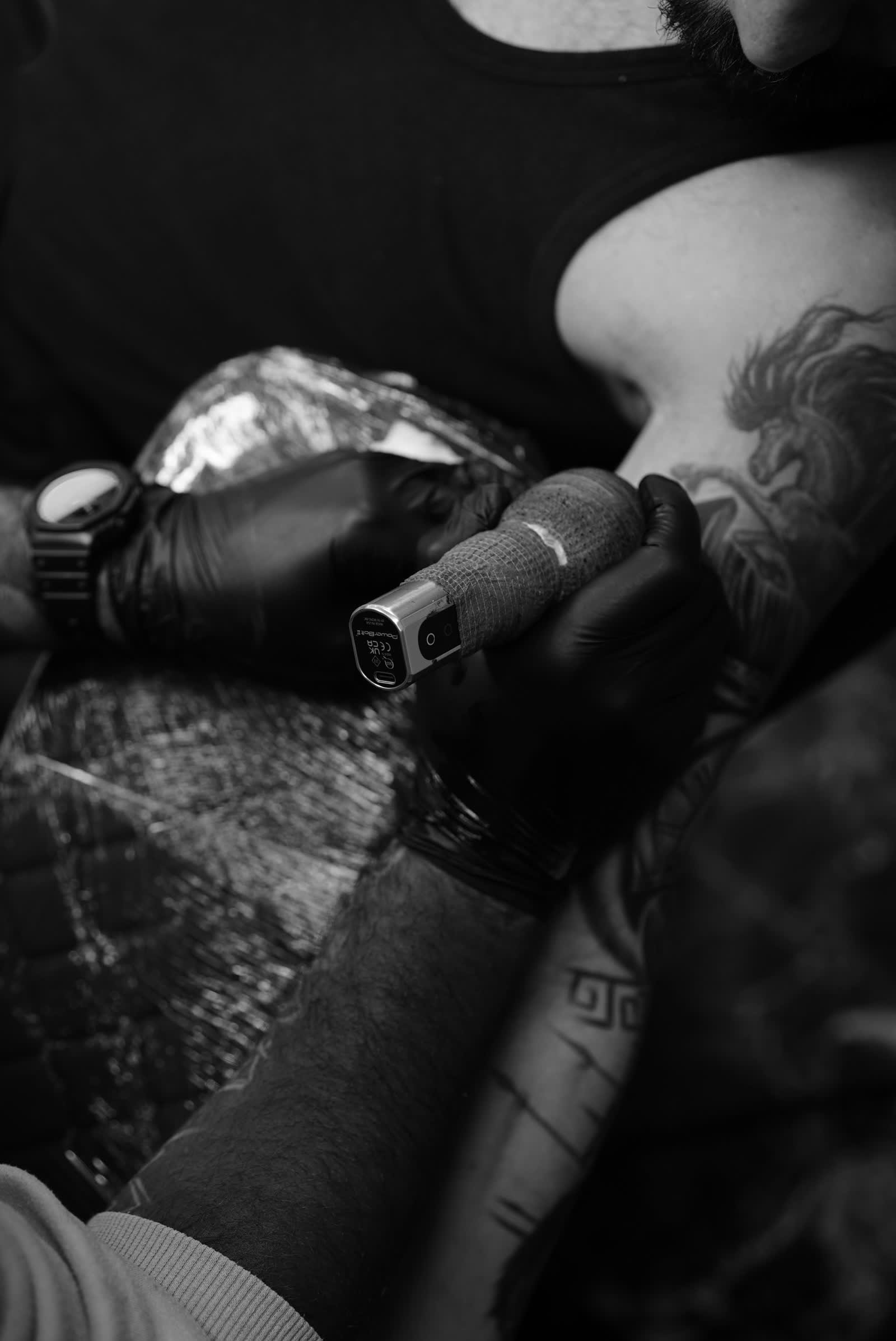 Tatuador segurando máquina, preto e branco